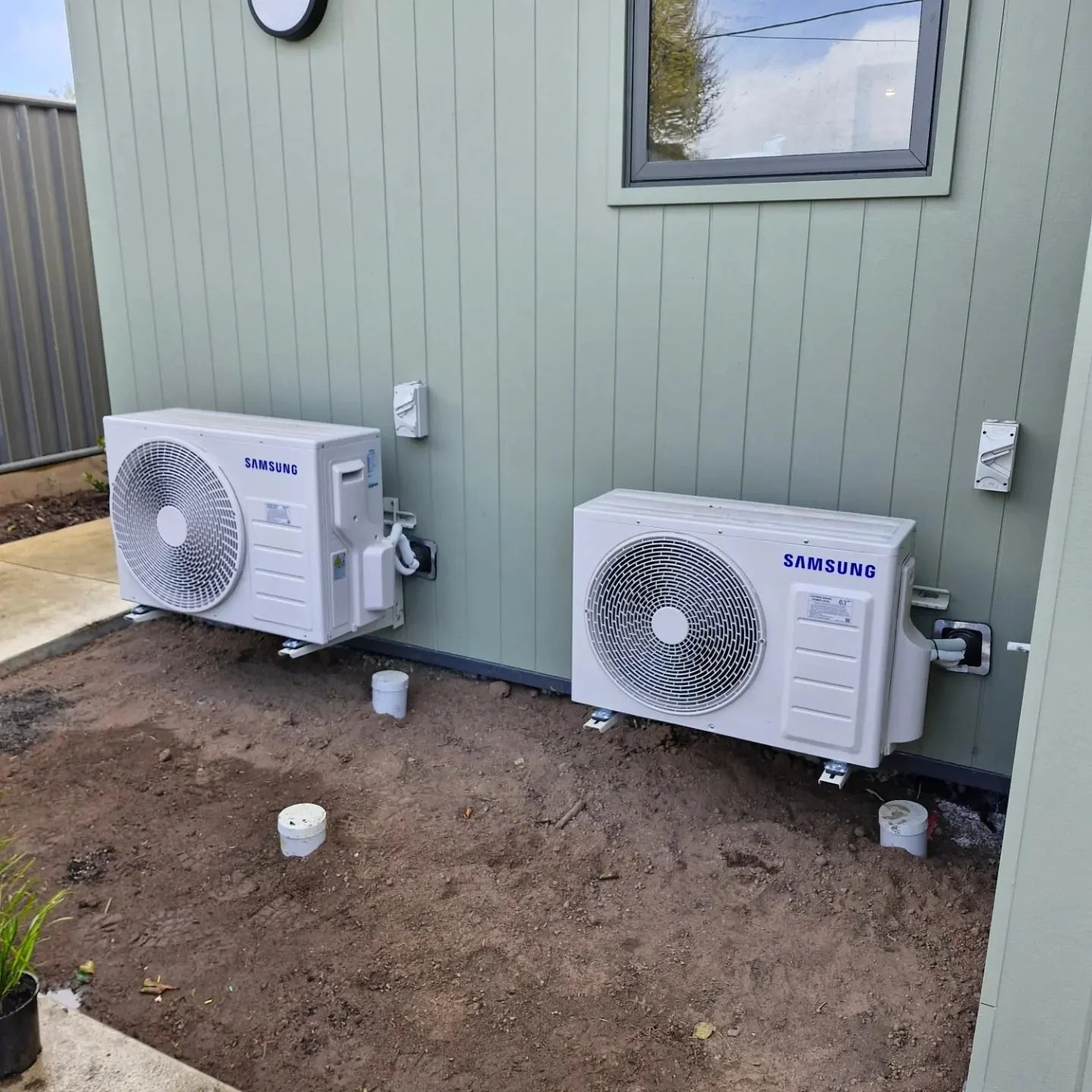 Two outdoor air conditioning compressor units installed against an exterior wall by a qualified Air Conditioning Electrician in Geelong.